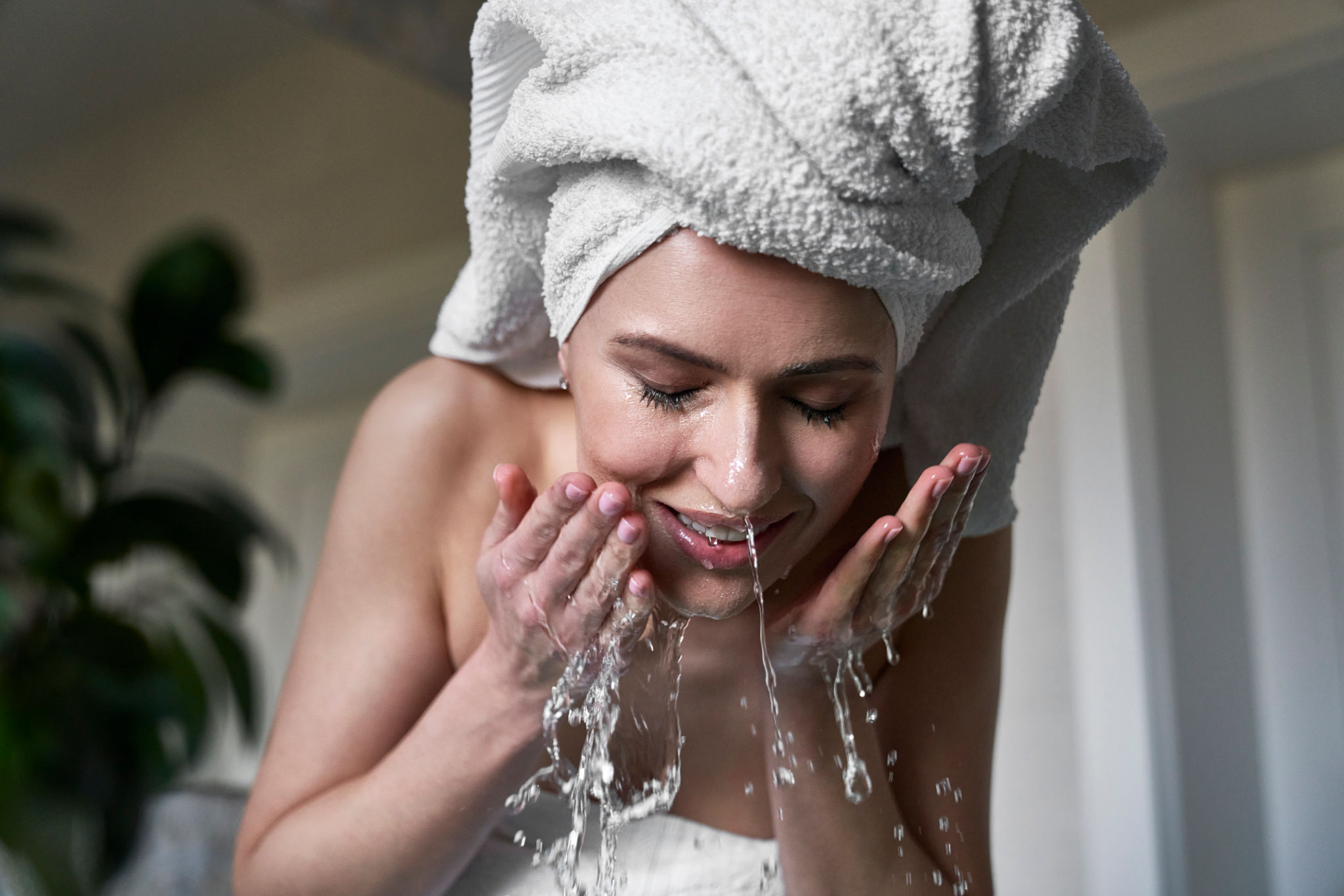 Front view of woman washing face with water in the bathroom Front view of woman washing face with water in the bathroom