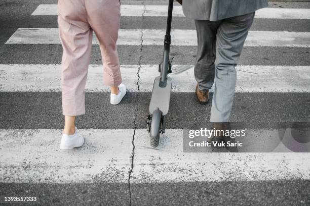 rear view of two people pushing electric scooter in formal business clothes - sustainable transportation stock pictures, royalty-free photos & images