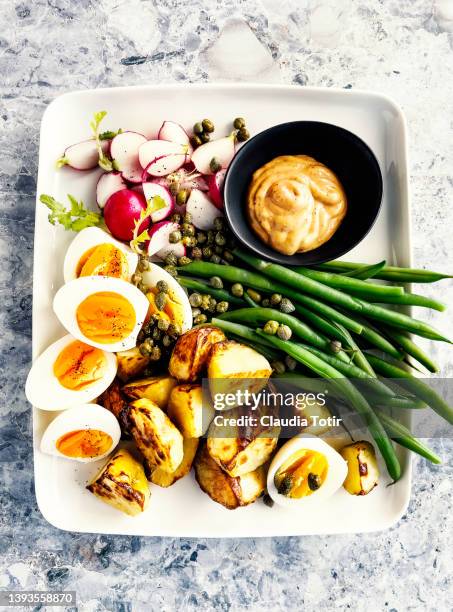 appetizer plate (green beans, hard-boiled eggs, and roasted potatoes with aioli) on gray background - aioli stock-fotos und bilder