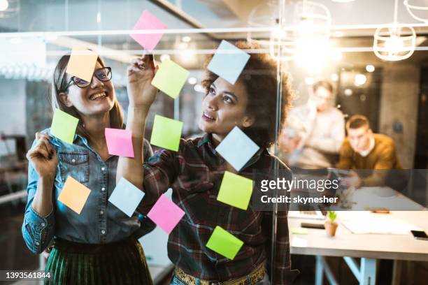 young creative women making mind map on a glass wall in the office. - etiketteren stockfoto's en -beelden
