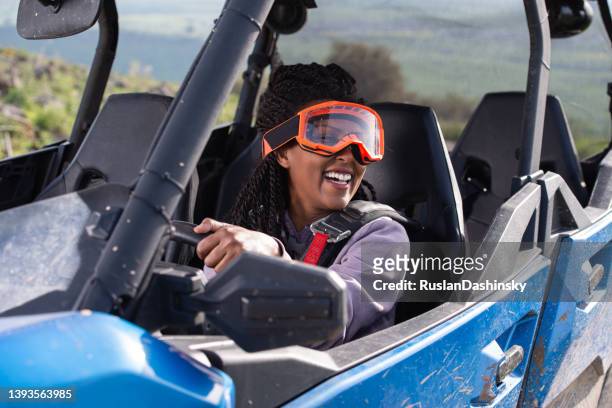 portrait of a happy woman driving a recreational off-highway, side-by-side (sxs) vehicle. outdoor pursuit, hobby, and leisure activity. - side by side atv stock pictures, royalty-free photos & images