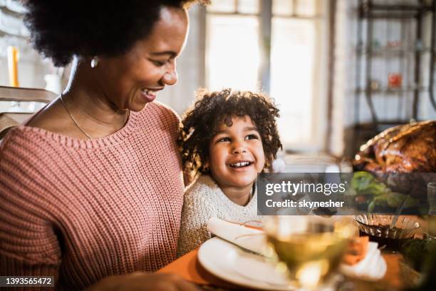happy black single mother and her daughter on thanksgiving meal at dining table. - african at dining table stockfoto's en -beelden