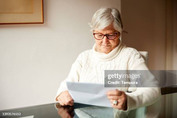 senior woman at home reading a letter. - message stock pictures, royalty-free photos & images