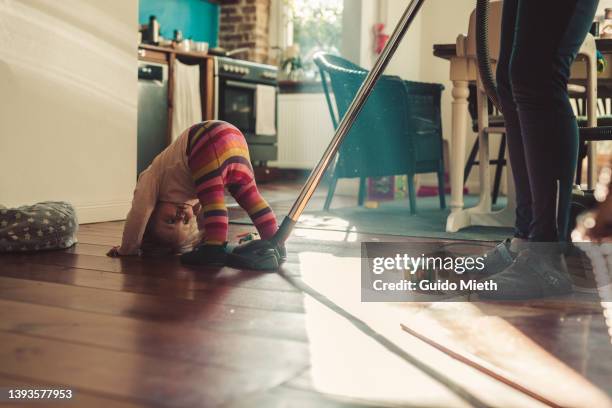 mother cleaning while little girl getting tired. - house cleaning stock pictures, royalty-free photos & images