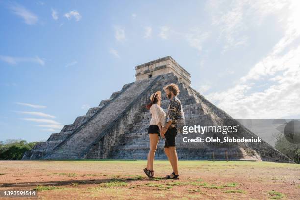 couple on the background of chichen itza pyramid in mexico - mayan people stockfoto's en -beelden