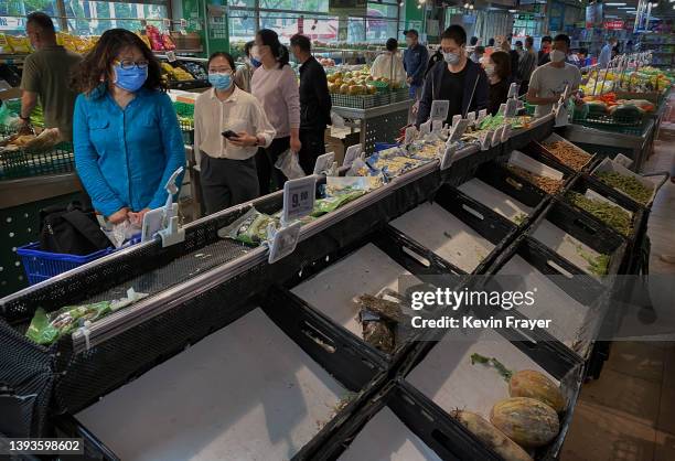 People shop for vegetables as some shelves are nearly empty after items being bought out at a supermarket in Chaoyang District on April 25, 2022 in...