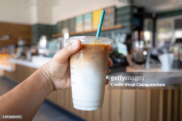 close-up of hand holding drink at cafe - iced coffee foto e immagini stock