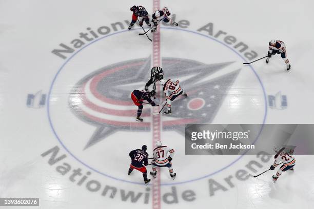 Cole Sillinger of the Columbus Blue Jackets and Ryan Nugent-Hopkins of the Edmonton Oilers battle for the puck in a face-off during the third period...