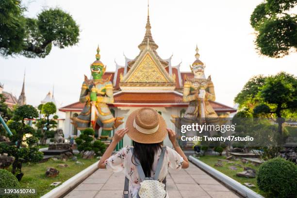 rear view of a woman in casual dress and sunhat traveling at wat arun temple in bangkok, thailand. - wat arun tempel stock-fotos und bilder