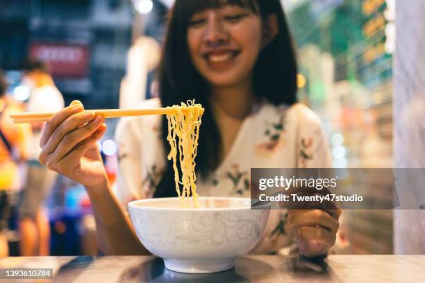 young asian woman enjoys eating chinese noodle street food at yaowarat bangkok chinatown in bangkok, thailand. - noodle stock pictures, royalty-free photos & images