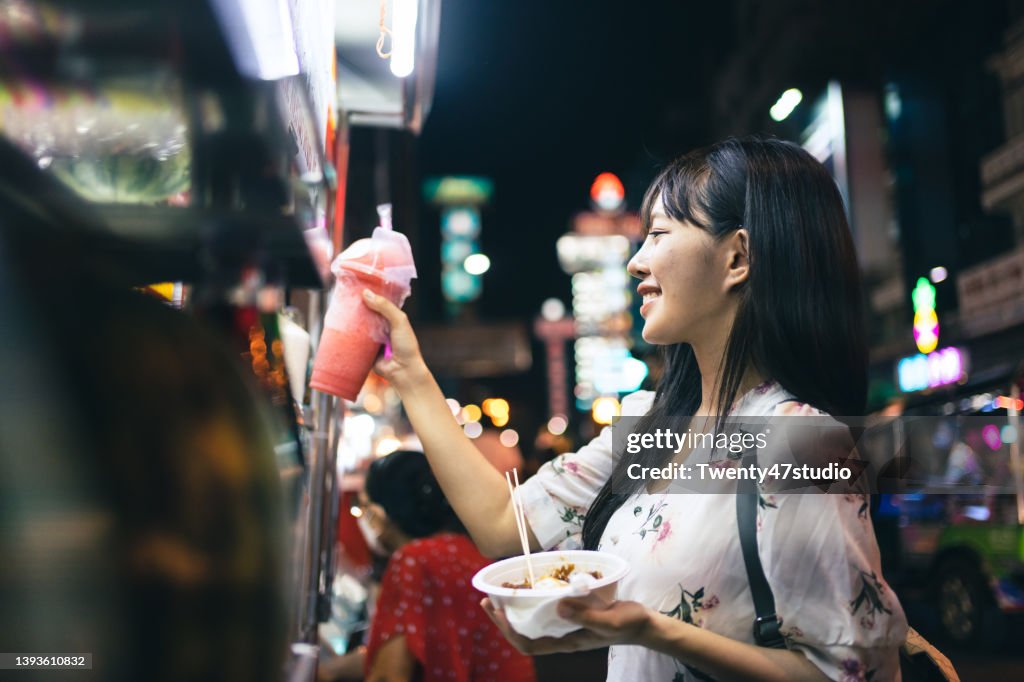 Young Asian woman enjoys a variety of street food at Yaowarat Bangkok Chinatown in Bangkok, Thailand.