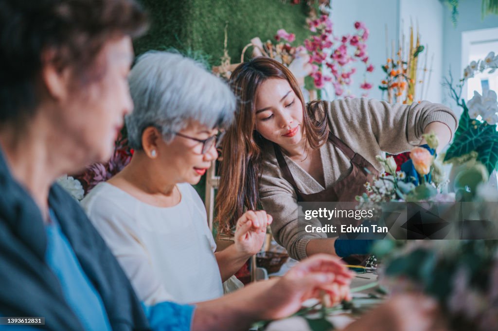 Asian chinese senior women learning flower arrangement from female florist at flower shop