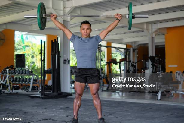 indonesian man lifting barbel at gym - barbell stock pictures, royalty-free photos & images