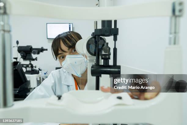 latin woman doctor by profession analyzes medical sample through state-of-the-art microscopy - herramientas profesionales stockfoto's en -beelden