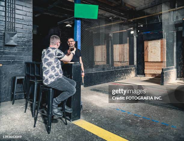 young gay men at the axe throwing game room - axe throwing stock pictures, royalty-free photos & images