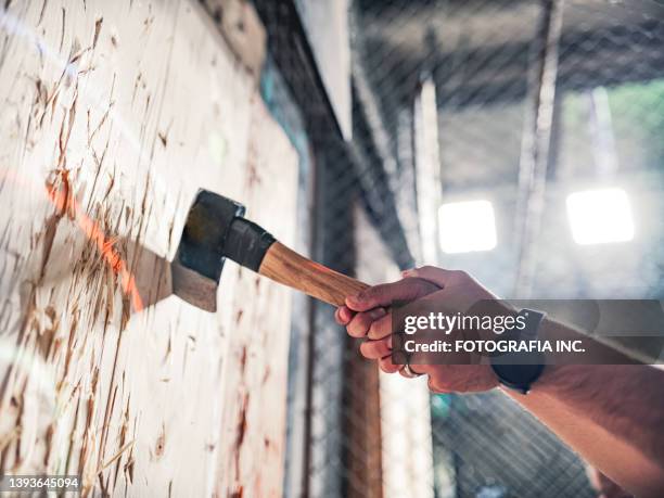 young gay man throwing axe at the game range - gooien stockfoto's en -beelden