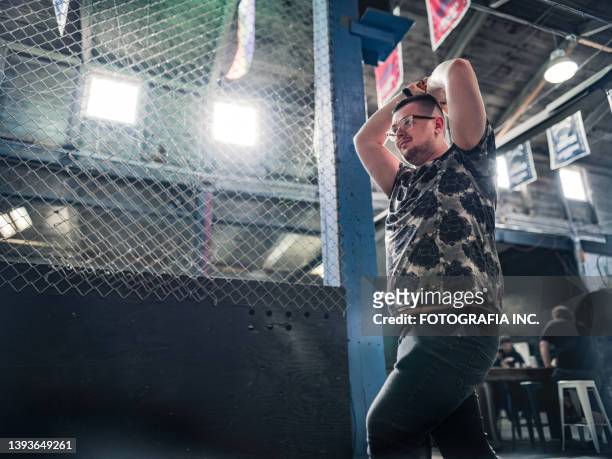 young gay man throwing axe at the game range - axe throwing stock pictures, royalty-free photos & images