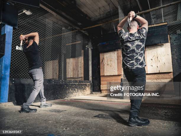 young gay men at the axe throwing game room - gooien stockfoto's en -beelden