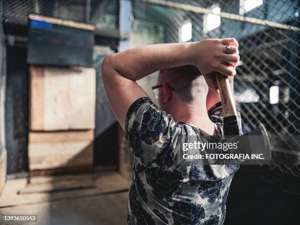 young gay man throwing axe at the game range - gooien stockfoto's en -beelden