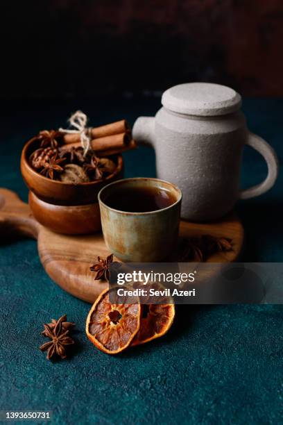 black tea in a small khaki green and rust effect ceramic cup without handle on a round wooden cutting board on a dark turquoise green rough floor - food photography dark background blue imagens e fotografias de stock