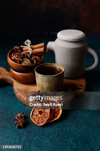 Black tea in a small khaki green and rust effect ceramic cup without handle on a round wooden cutting board on a dark turquoise green rough floor Black tea in a small khaki green and rust effect ceramic cup without handle on a round wooden cutting board on a dark turquoise green rough floor