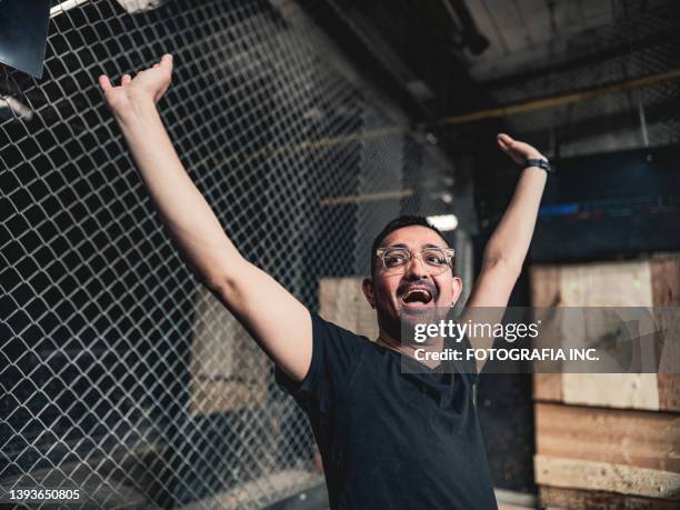 young gay man throwing axe at the game range - axe throwing stock pictures, royalty-free photos & images