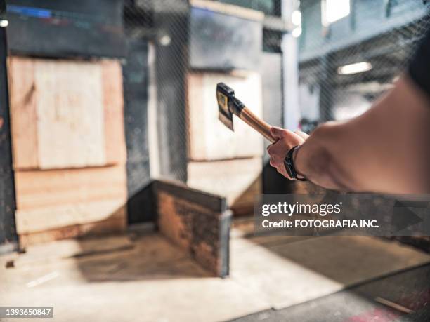 young gay man throwing axe at the game range - axe throwing stock pictures, royalty-free photos & images