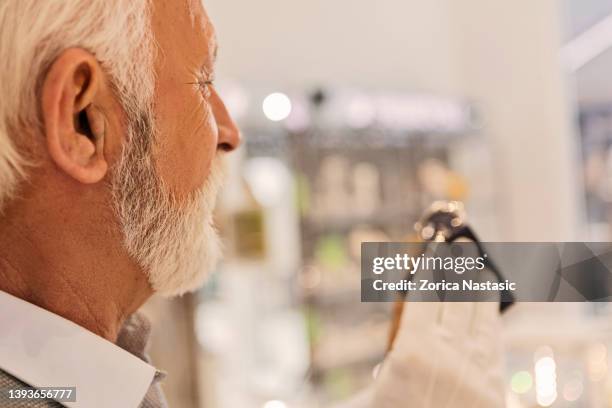 senior man in jewelry store selling wristwatches - rag time stockfoto's en -beelden