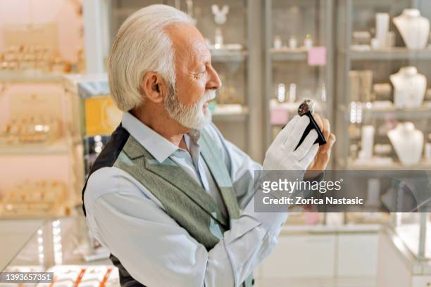 senior man wiping wristwatch with a piece of cloth - jeweller bildbanksfoton och bilder