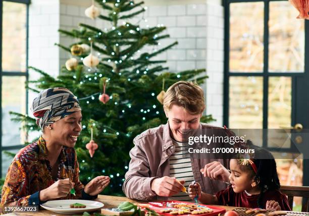 black mother and daughter decorating christmas cookies with young man - men costume black and white stock-fotos und bilder