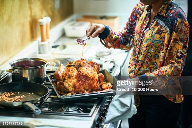 woman basting turkey in roasting tin for christmas dinner - christmas turkey fotografías e imágenes de stock