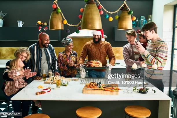 young man photographing christmas dinner with phone - christmas dinner stock pictures, royalty-free photos & images