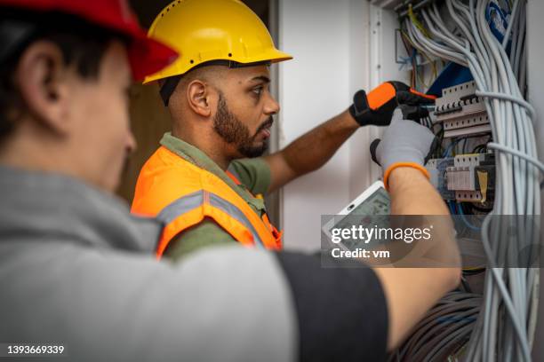 électricien afro-américain inspectant l’installation, dessins sur tablette numérique - paire de gants noirs photos et images de collection