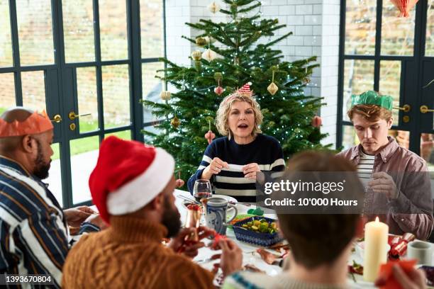 family telling jokes from christmas crackers at dinner table - 聖誕拉炮 個照片及圖片檔