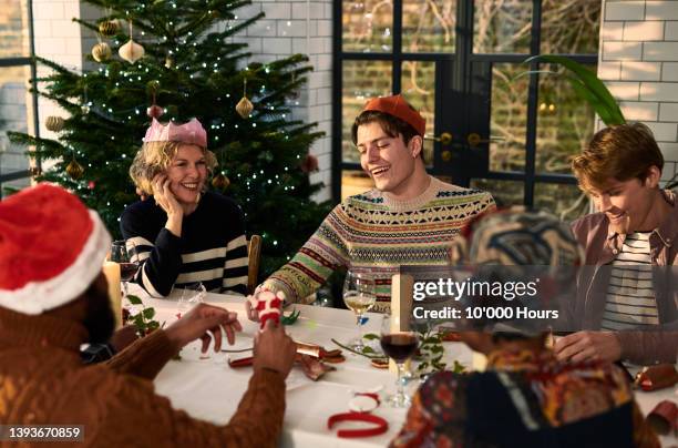 cheerful family sitting down after christmas dinner playing games - tradizione foto e immagini stock
