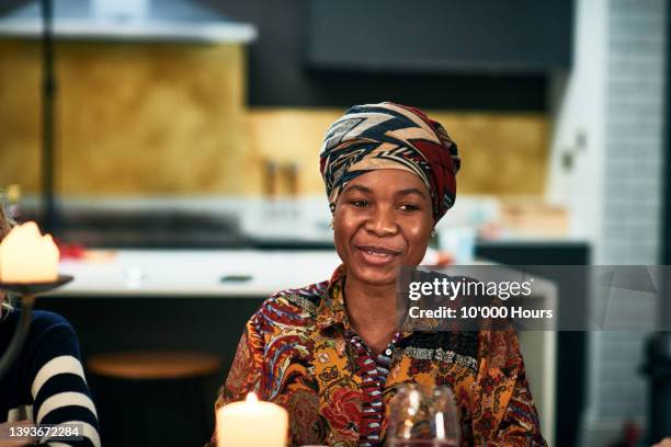 beautiful black woman in her 30s smiling at dinner table - head tie stock pictures, royalty-free photos & images