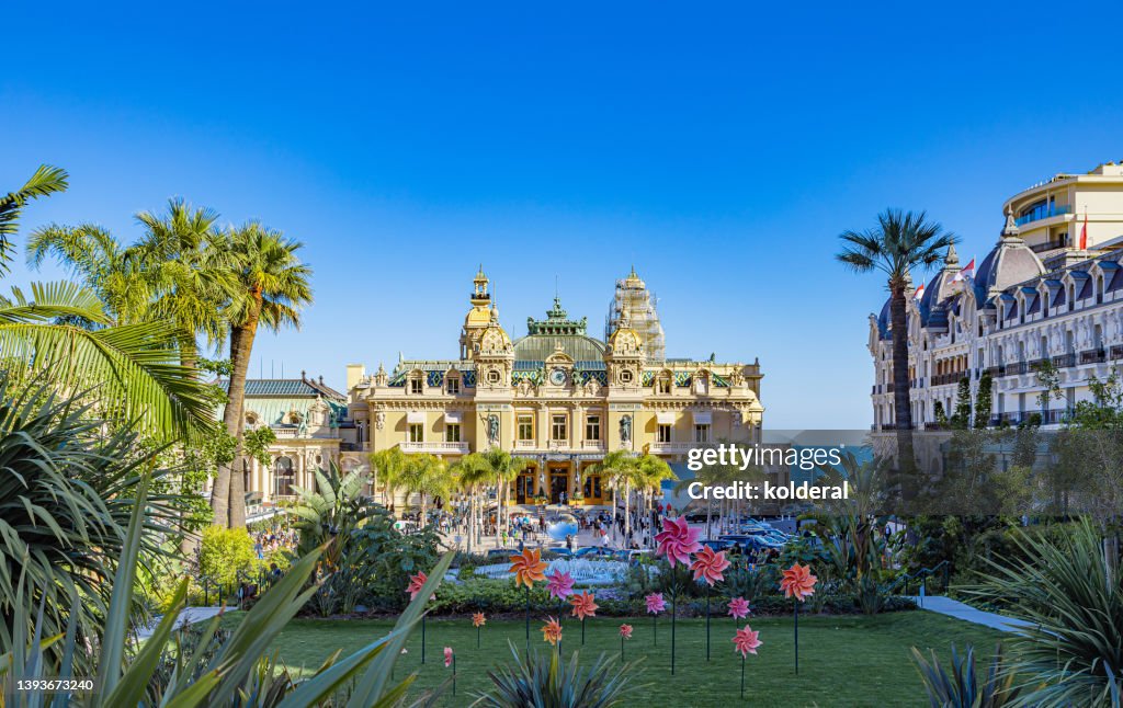 Monte Carlo Grand Casino building and casino garden decorated with pinwheels, Monte Carlo at midday in bright sunlight against clear blue sky
