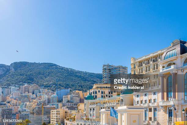 monte carlo luxury property, luxury hotels and theater of princess grace in bright sunlight against green hills and clear blue sky - monaco nice stock-fotos und bilder