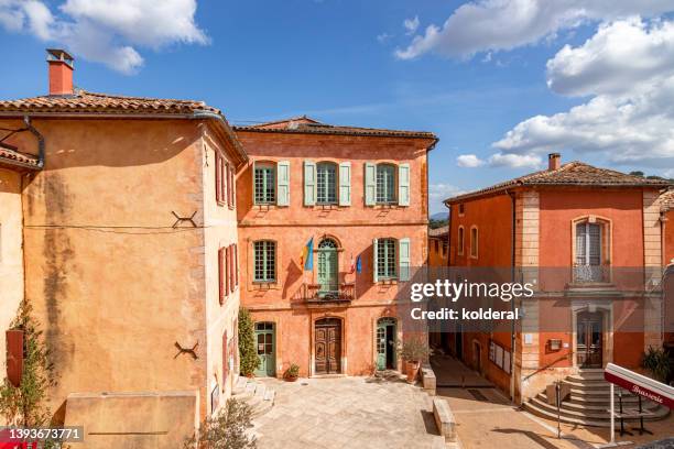 picturesque village of roussillon, terracotta colored traditional buildings against blue sky - vaucluse stock pictures, royalty-free photos & images