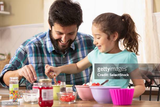 father and daughter putting sprinkles on ice cream - ice cream sundae stock pictures, royalty-free photos & images