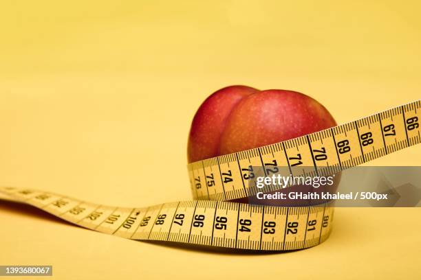 slim body,close-up of apple with tape measure on yellow background - fasting stock pictures, royalty-free photos & images