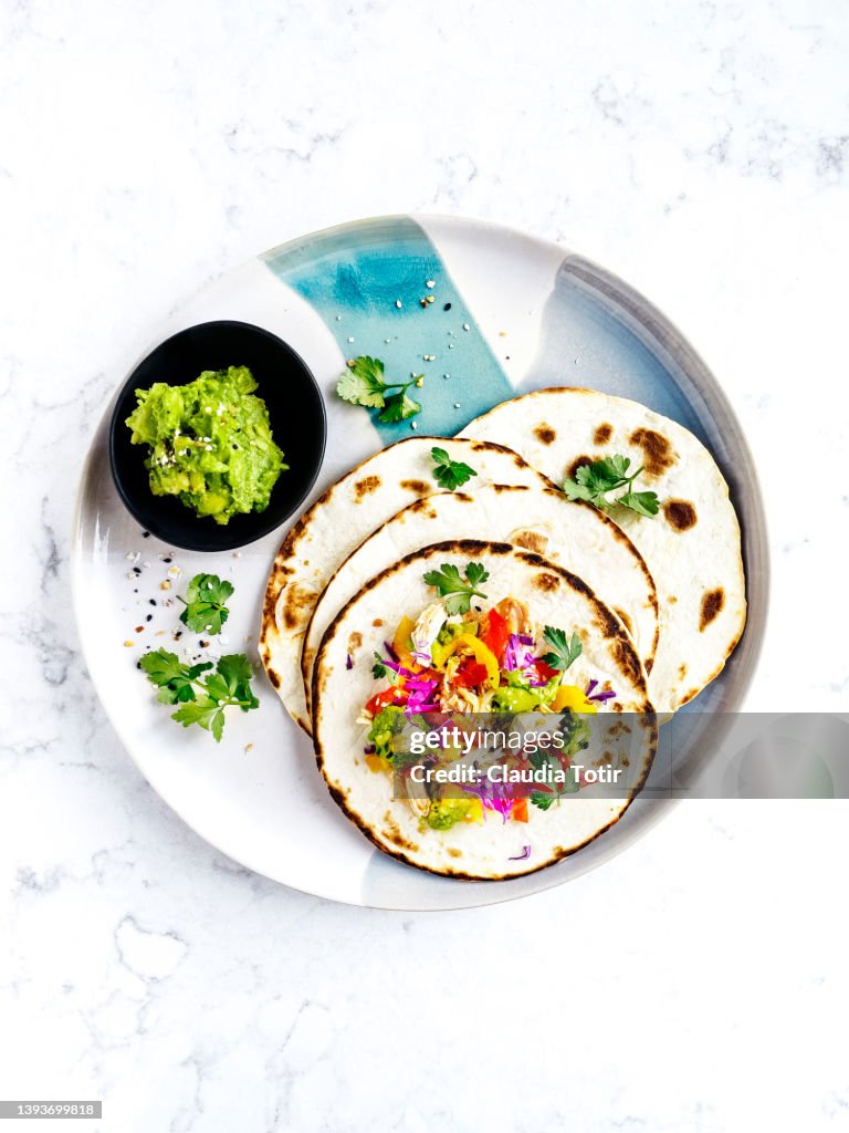 Chicken tacos on a plate on white, marble background