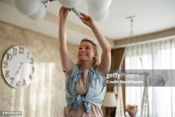 woman replaces an electric bulb in ceiling light fixture - led lampje stockfoto's en -beelden