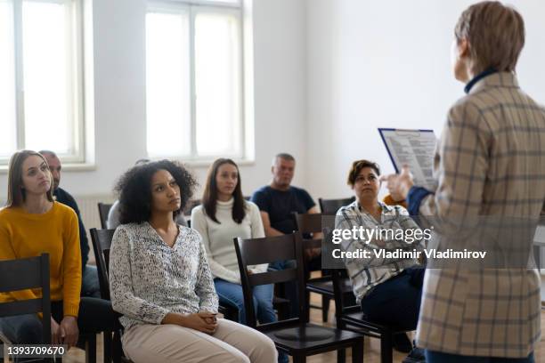 a woman standing in front of a audience - employee welfare stockfoto's en -beelden