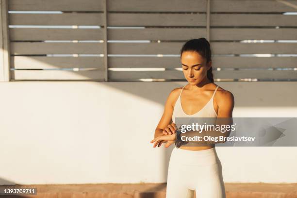 slim athletic woman using fitness tracker to start workout. smart watches for control exercising  and heart rate - activity tracker stock pictures, royalty-free photos & images