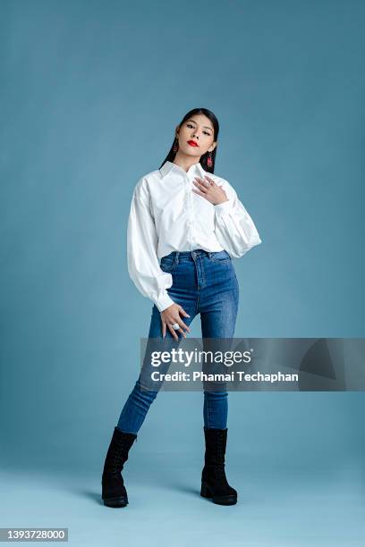 beautiful woman front of plain background - red jeans stock pictures, royalty-free photos & images