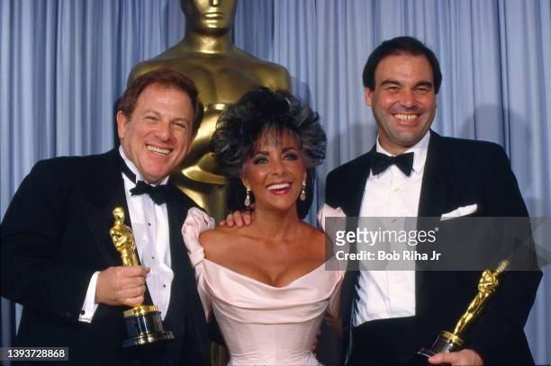 Elizabeth Taylor with Oscar Winners Director Oliver Stone and Producer Arnold Kopelson for Best Picture "Platoon", backstage at the Academy Awards...