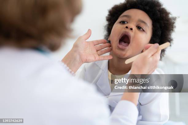 image of female pediatrician examining african boy  sick. - throat photos - fotografias e filmes do acervo