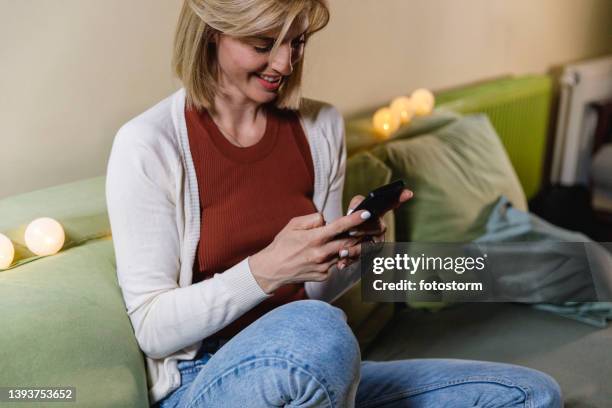 woman lounging on the sofa and texting with friends - meme text stock pictures, royalty-free photos & images