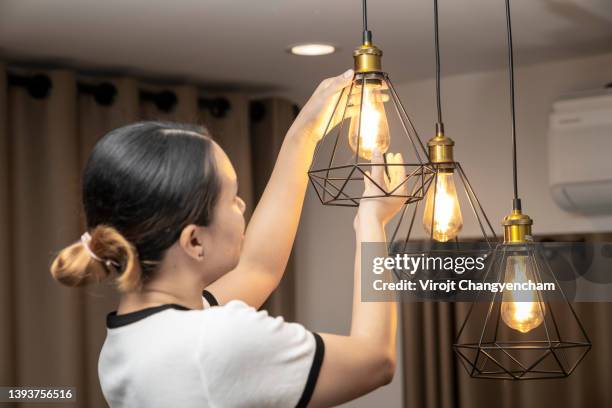 female changing light bulb at home - fitting stockfoto's en -beelden